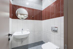 Through doorway of contemporary bathroom interior with ceramic washbasin under mirror and white toilet
