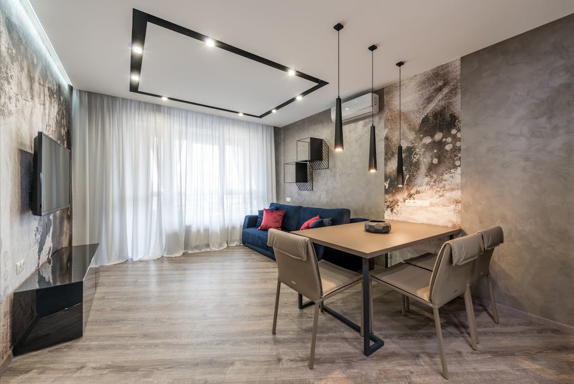 Modern TV hanging on wall in front of soft couch and dining table