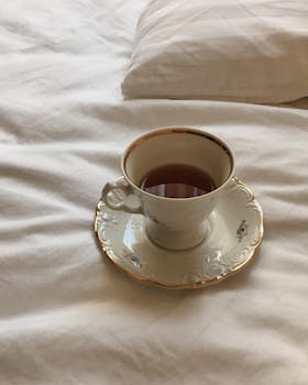 Elegant porcelain cup with tea on a plush bed, capturing a serene morning vibe.