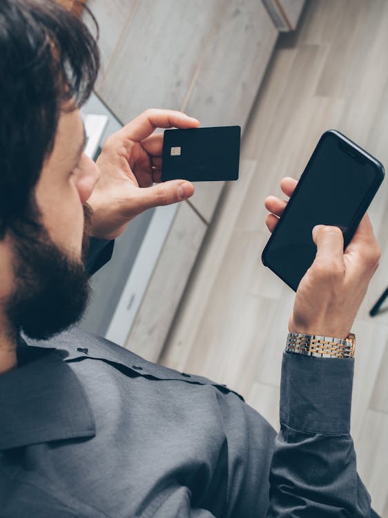 Man in Gray Sweater Holding Black Smartphone