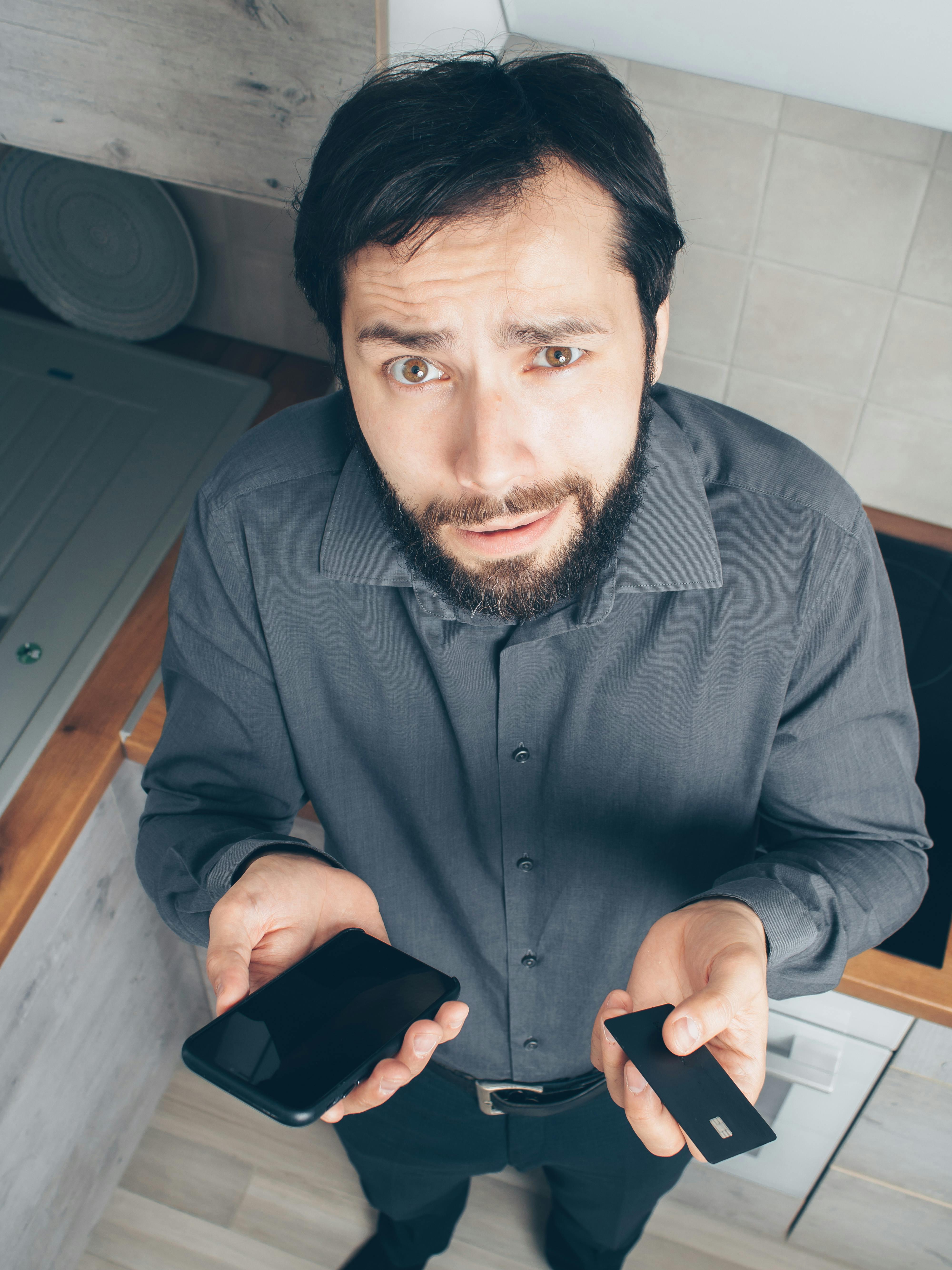 man in black dress shirt holding black smartphone