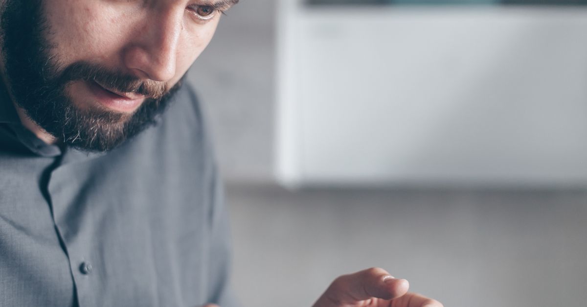 Person looking at a smartphone with a student loan forgiveness app notification, surprised expression, cozy living room background