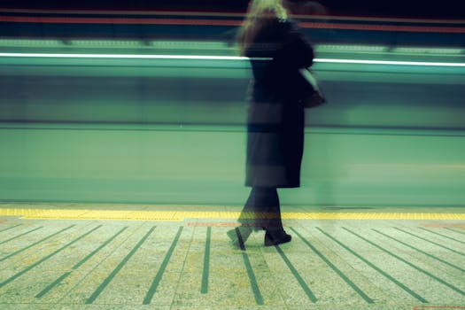 Woman waiting at Istanbul train station, blurred motion capturing a fast-moving train.