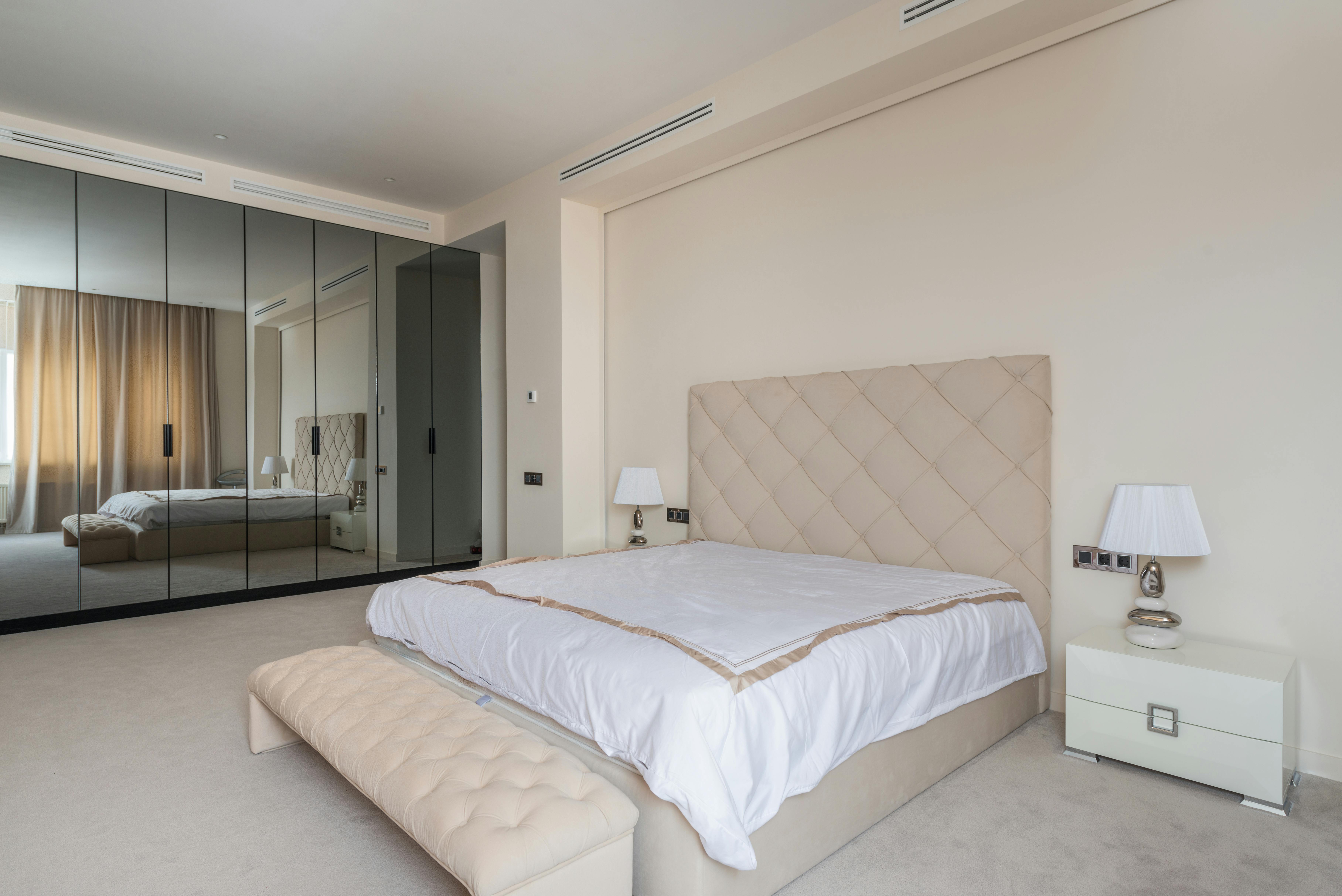 cozy bed and ottoman bench in elegant bedroom with wardrobe