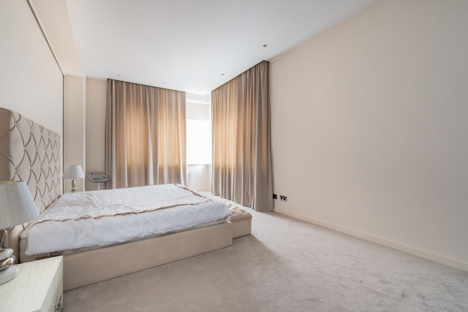 Interior of classy styled bedroom with comfortable bed and nightstands decorate with elegant lamps in spacious apartment