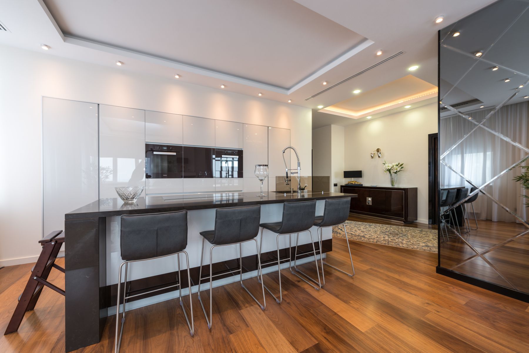 Modern studio kitchen with a continuous wall of pale floor-to-ceiling cabinetry