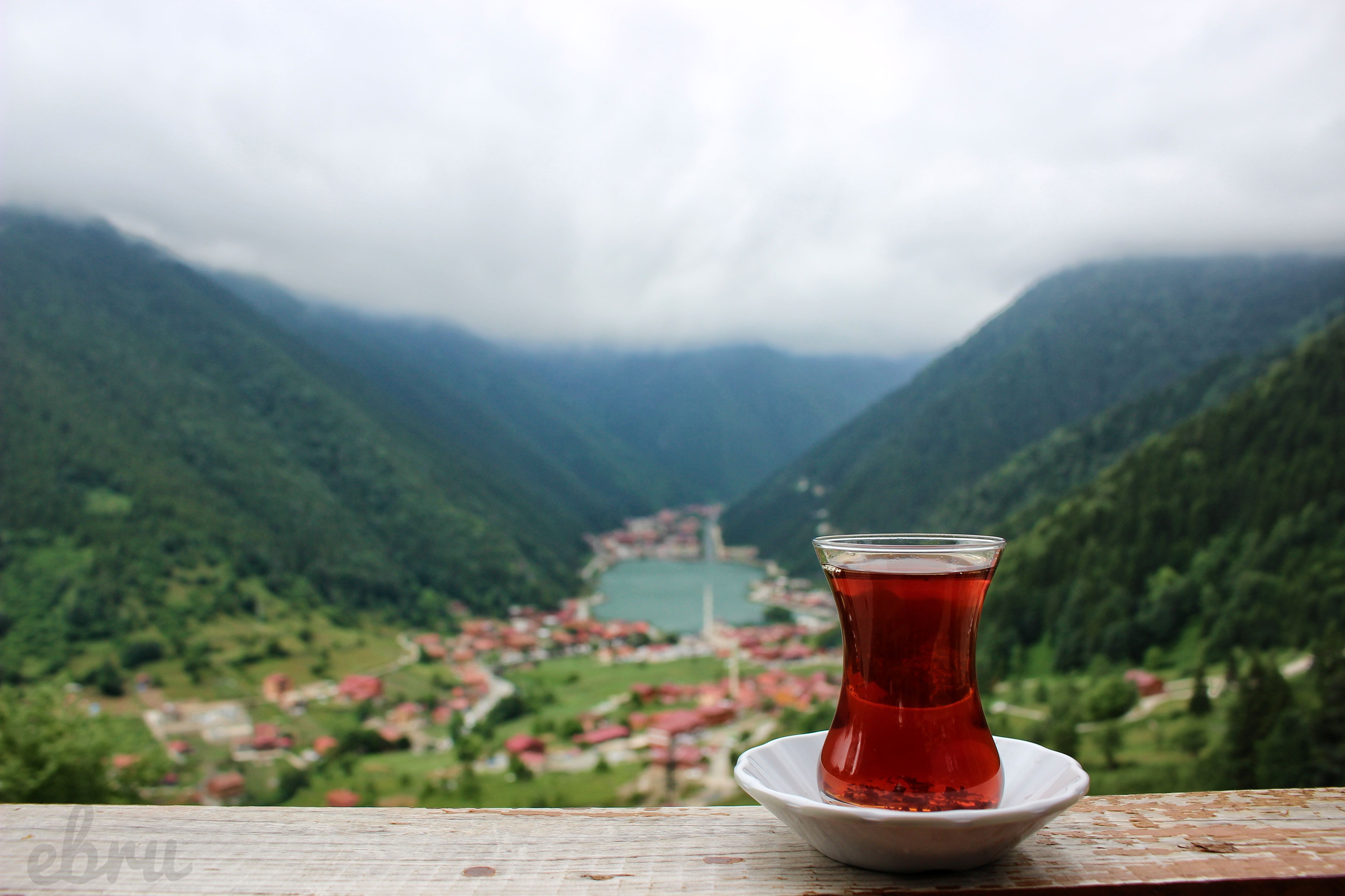 Enjoy a serene view of traditional Turkish tea with a misty mountain backdrop, creating a peaceful outdoor atmosphere.