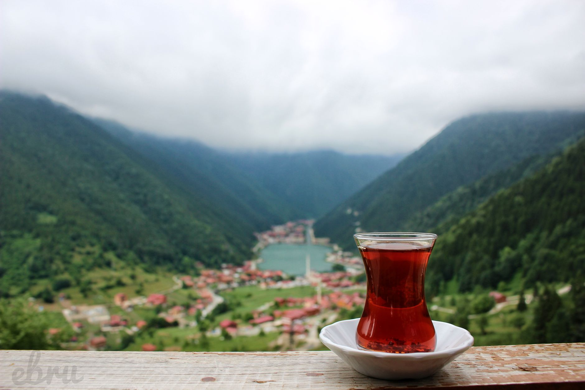 Enjoy a serene view of traditional Turkish tea with a misty mountain backdrop, creating a peaceful outdoor atmosphere.