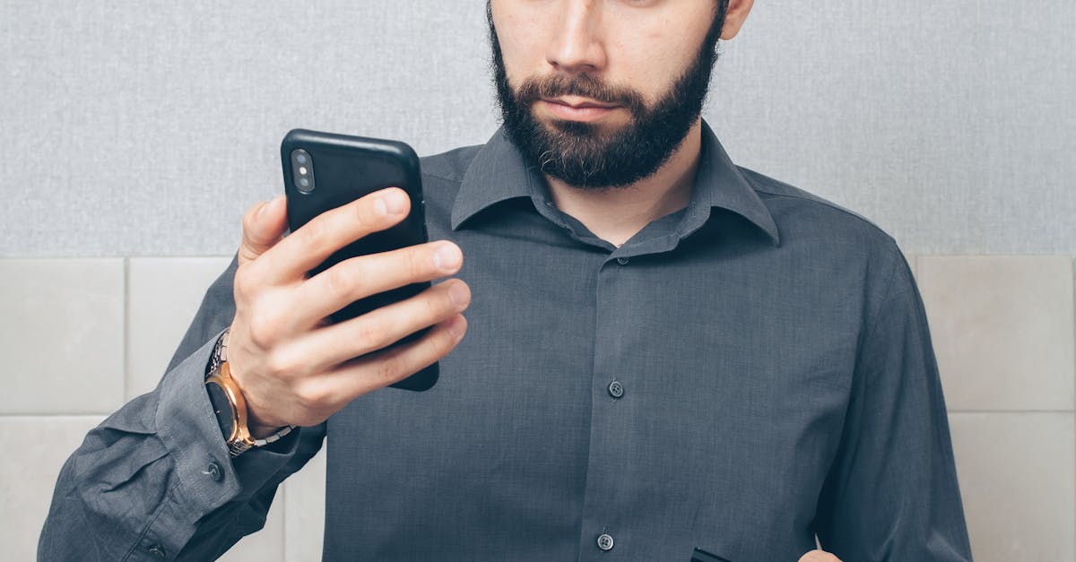 Photo by Mikhail Nilov An adult man in a gray shirt looks concerned while using a smartphone and holding a credit card indoors.