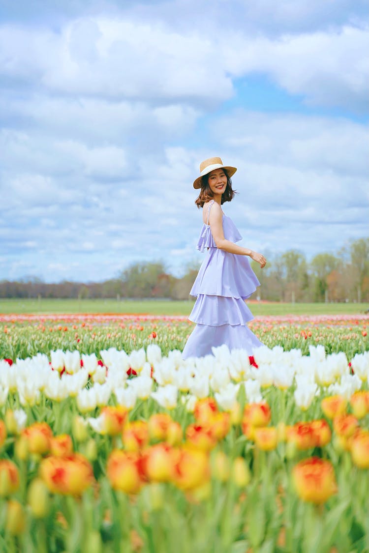 Woman In Hat Walking In Tulips Field