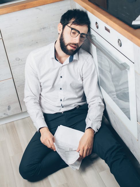 Man in White Dress Shirt and Black Pants Sitting on White Wooden Chair