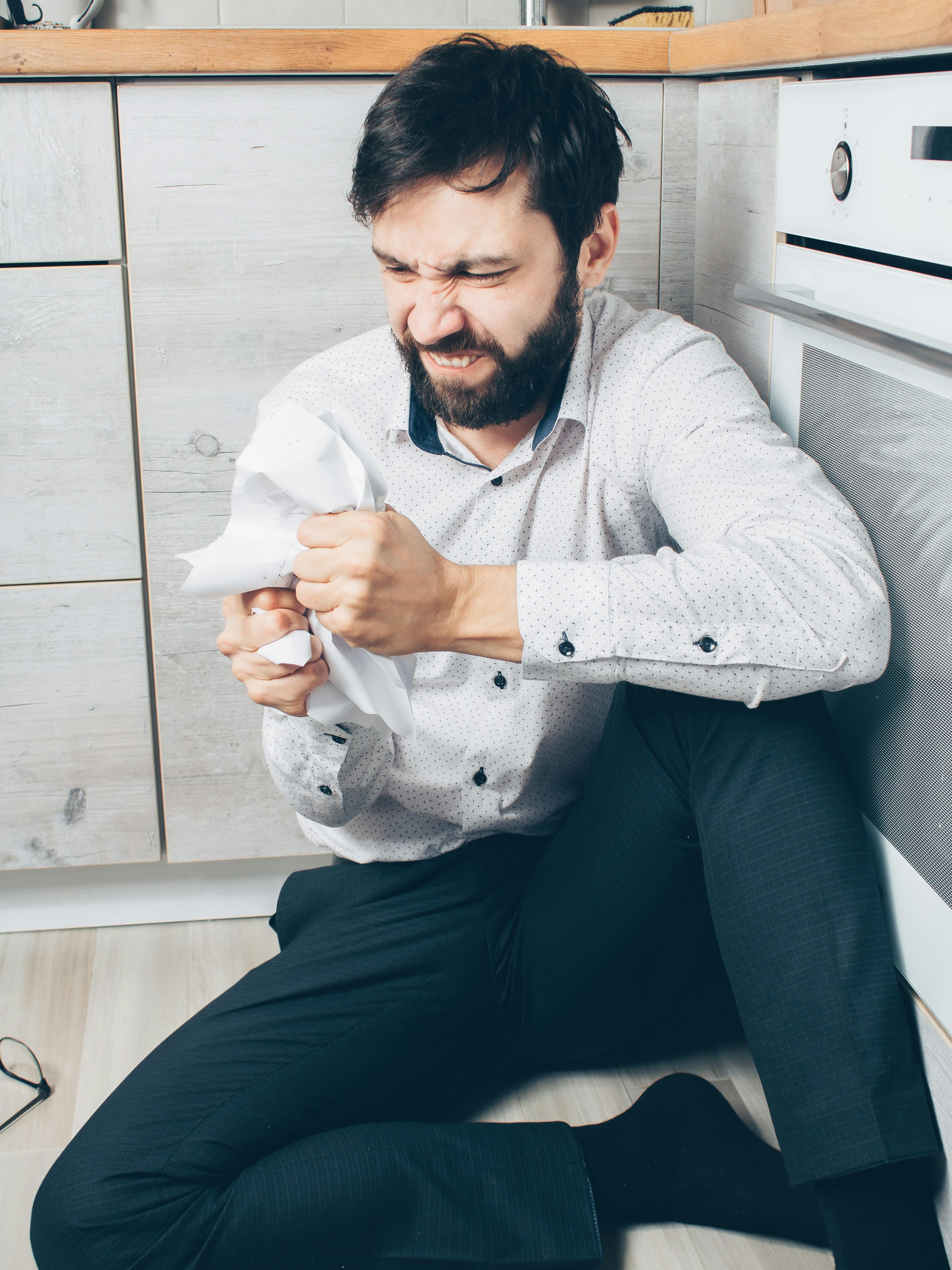 man in white dress shirt and black pants sitting on white wooden cabinet