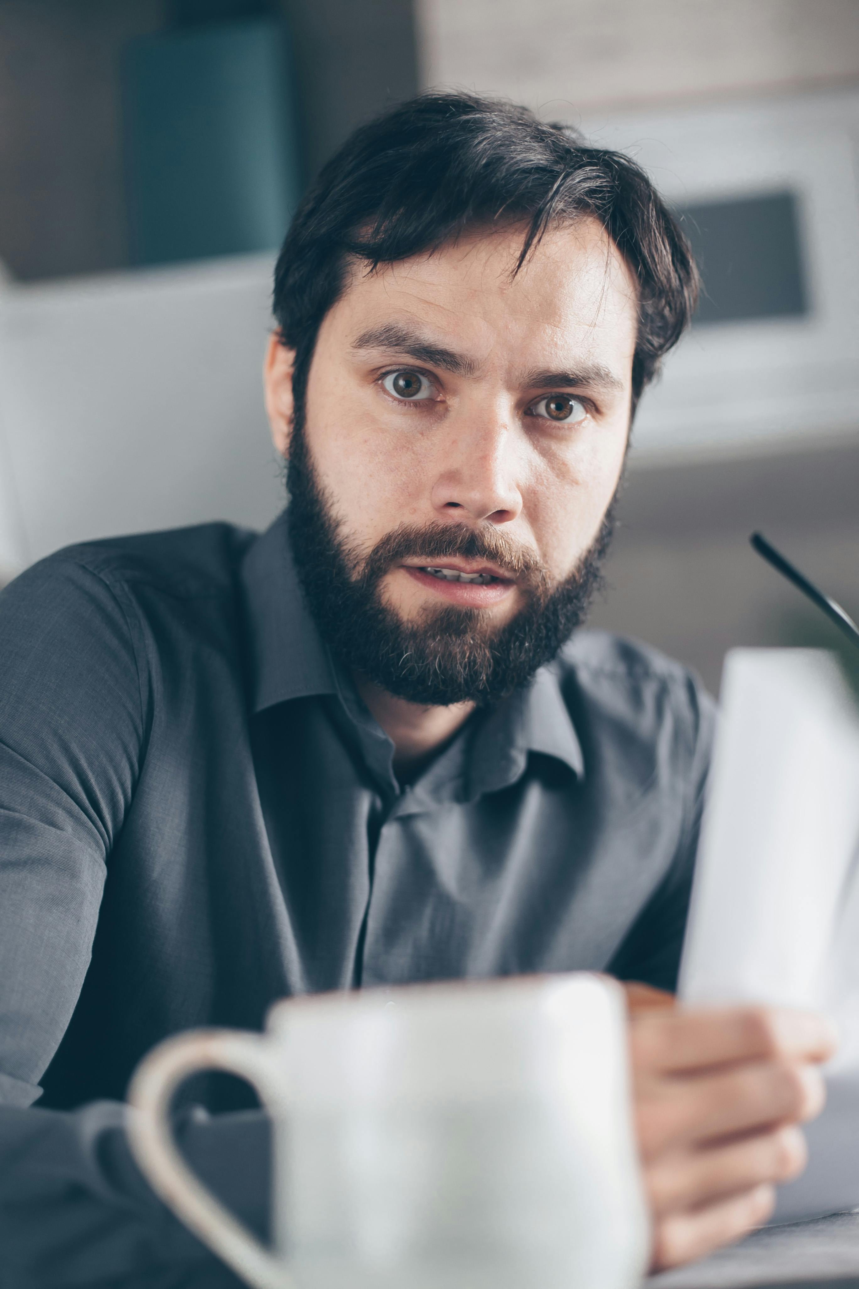 man in black polo shirt holding white ceramic mug