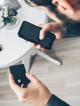 A man using a smartphone and credit card for an online payment, showcasing digital finance concepts.