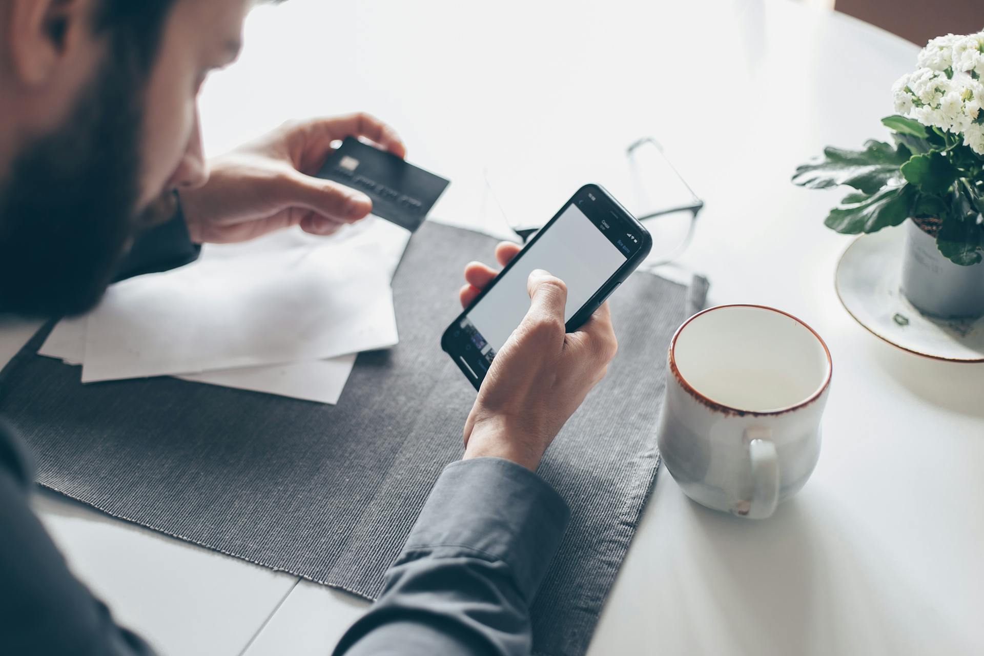 Man with a smartphone processing an online payment with a credit card. Soft light, modern lifestyle.