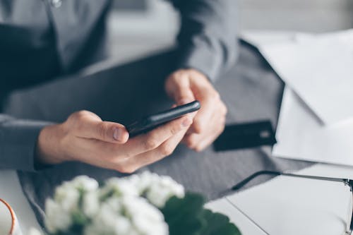 Person in Gray Long Sleeve Shirt Holding Black Smartphone