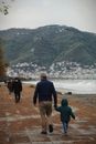 Unrecognizable man wearing mask and child walking together on embankment