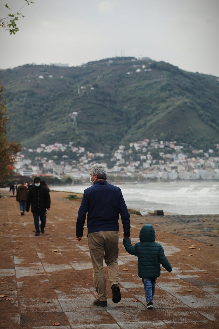 Unrecognizable Man Wearing Mask And Child Walking Together On Embankment