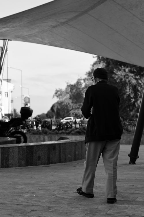 Free Black and white of back view of elderly male wearing blazer and trousers and face mask walking in city square Stock Photo
