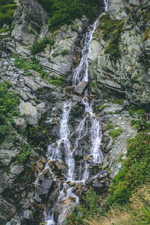 Free A picturesque waterfall cascading over rocks in a lush mountain landscape. Stock Photo