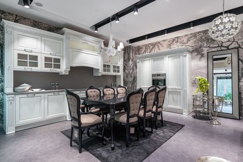 Free Interior of design of kitchen in classical style with white wooden cupboard and dining table surrounded with chairs Stock Photo