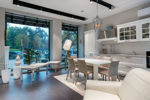 Free Interior of spacious studio apartment with dining table placed near white kitchen cabinets and soft couch Stock Photo