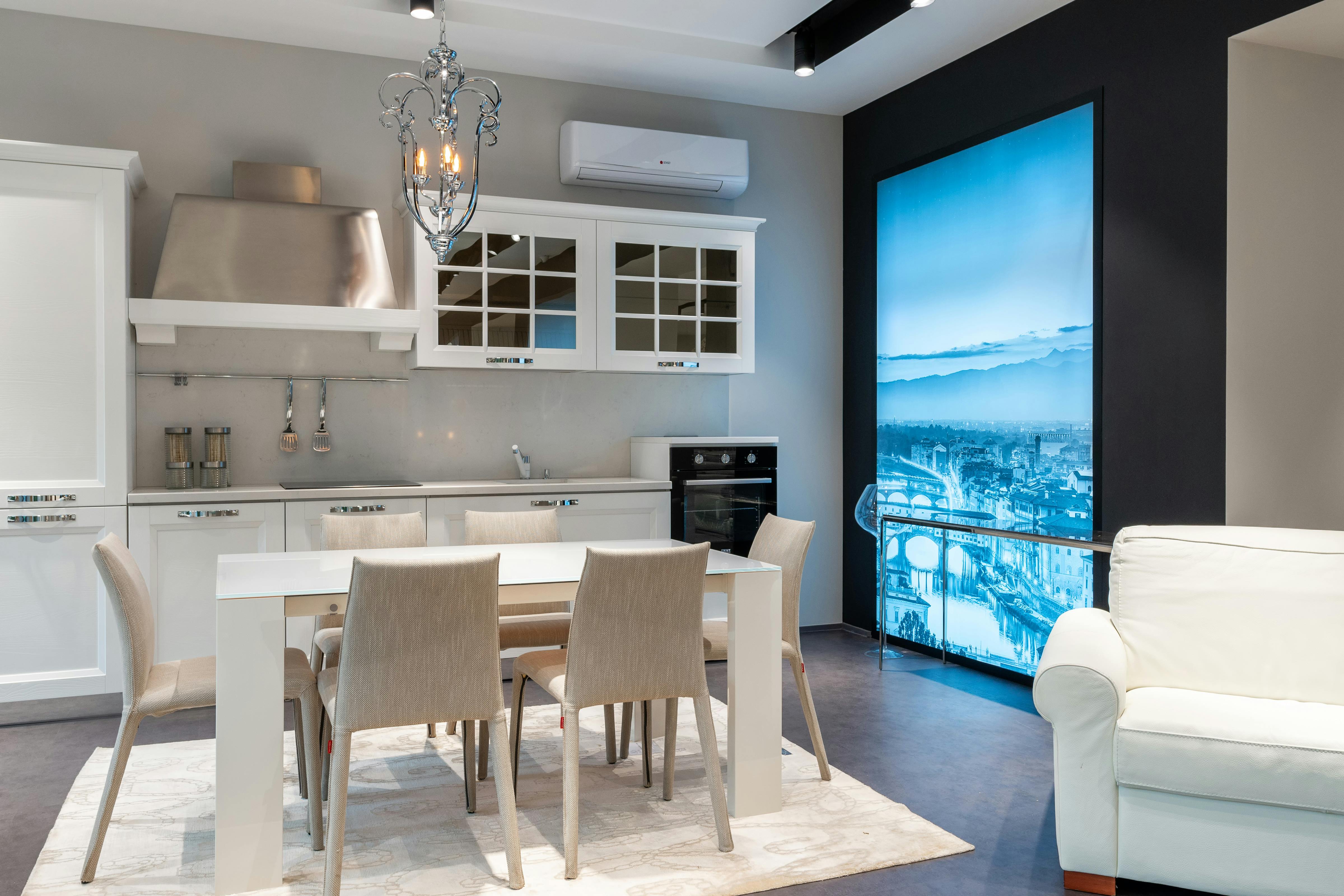 interior of stylish light kitchen with white furniture and dining area