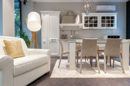 Free Comfortable white armchair with glowing lamp placed near dining table in spacious elegant kitchen in modern apartment Stock Photo