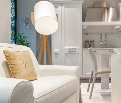 Stylish modern apartment interior featuring a cozy white armchair, elegant kitchen, and contemporary decor.