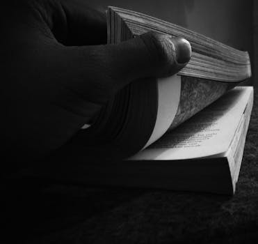 一只手翻阅书本的黑白特写，非常适合表现教育和阅读的概念