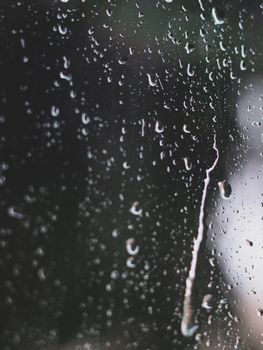 Close-up of a glass window covered in raindrops, capturing the mood of a rainy day.