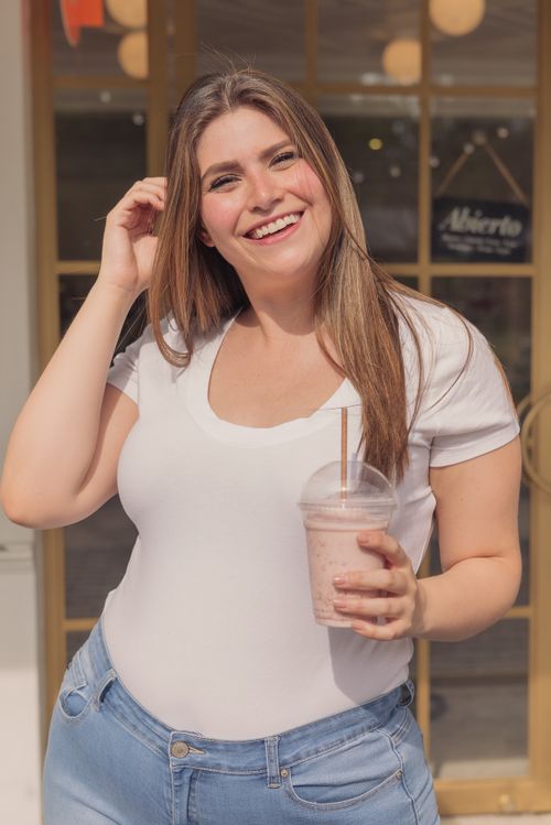 Free Happy woman with long hair enjoying a milkshake outdoors, showcasing body positivity and a joyful lifestyle. Stock Photo