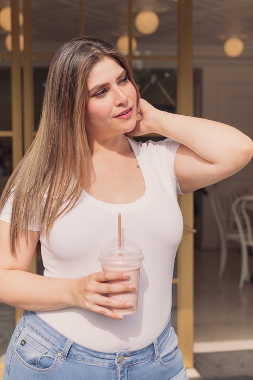 Beautiful Woman in a White Shirt Posing while Holding a Plastic Cup