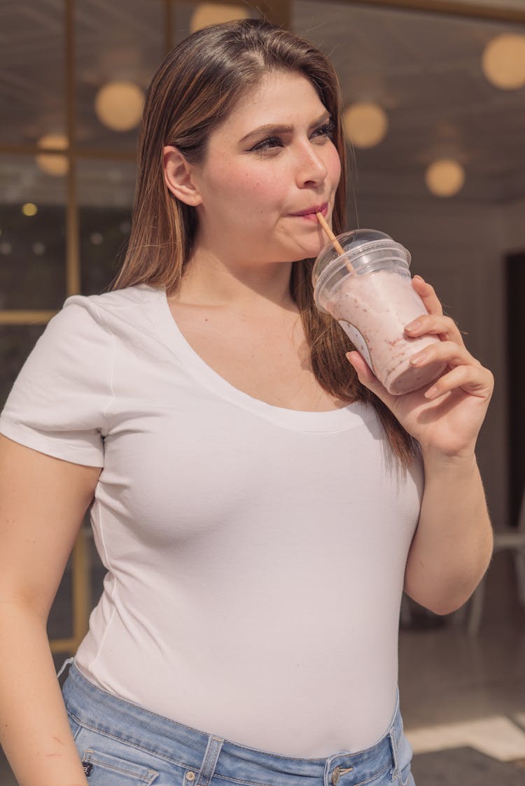 Woman In A White Scoop Neck Shirt Drinking Milkshake From A Plastic Cup