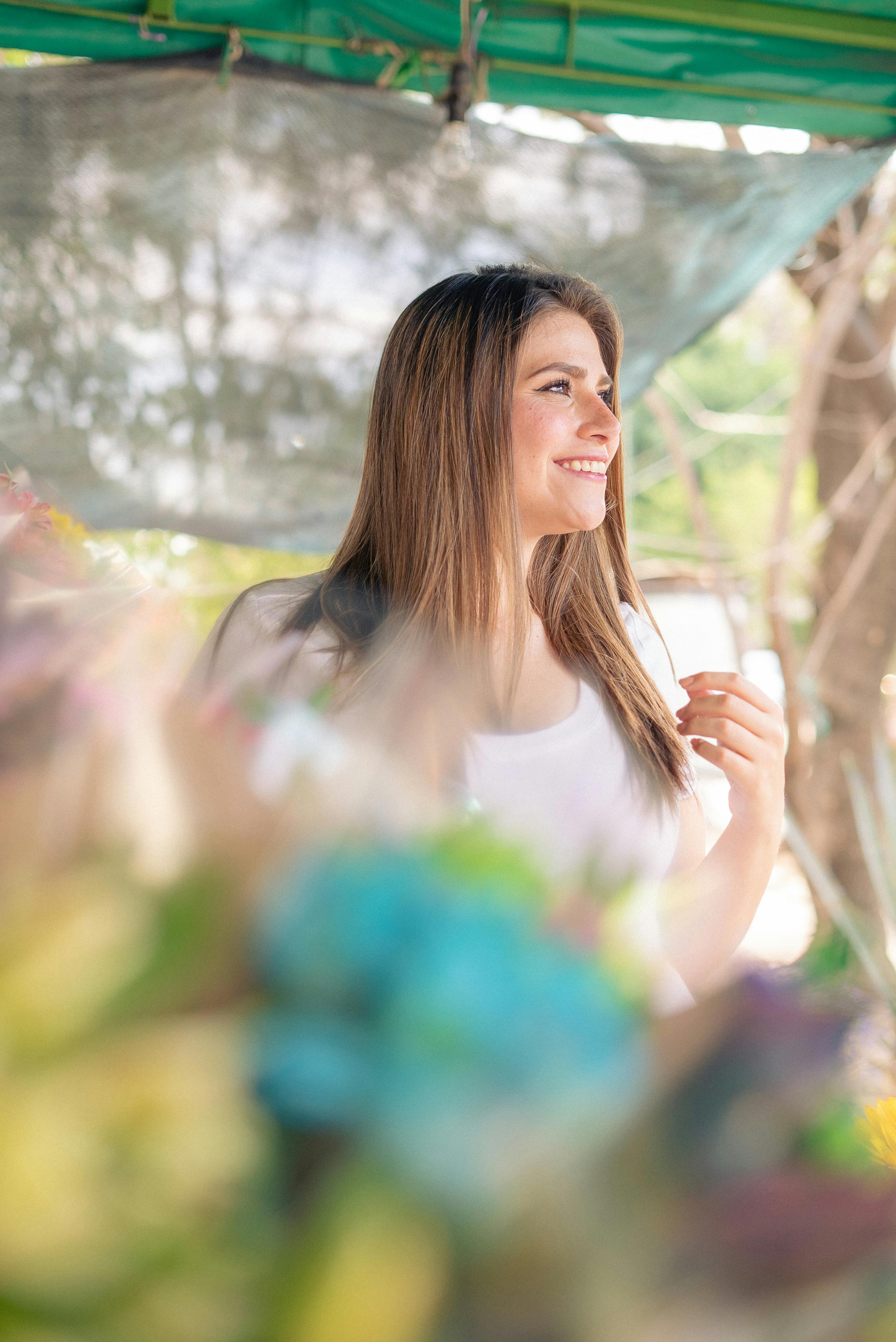 一个长发微笑的女人的肖像，拥抱一个阳光明媚的日子，户外与大自然