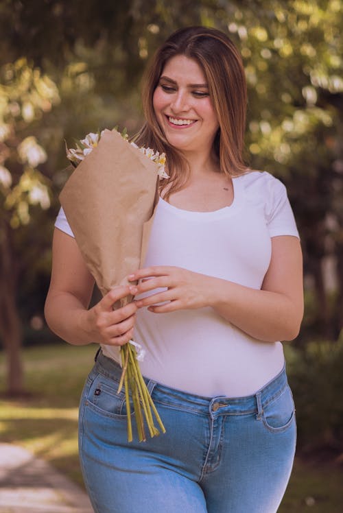 Selective Focus Photo of a Woman Looking at a Bouquet of Flowers