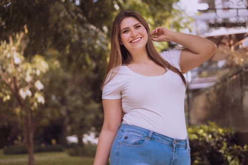Free A cheerful plus-size Hispanic woman posing confidently in a serene outdoor setting. Stock Photo