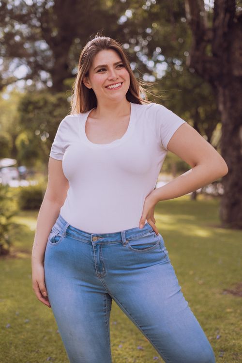 Free Happy woman in casual attire smiling outdoors, enjoying a sunny day. Stock Photo
