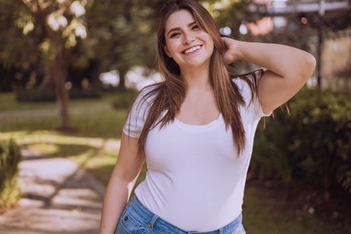 Free A joyful woman in a white shirt smiles outdoors, embodying confidence and positivity. Stock Photo