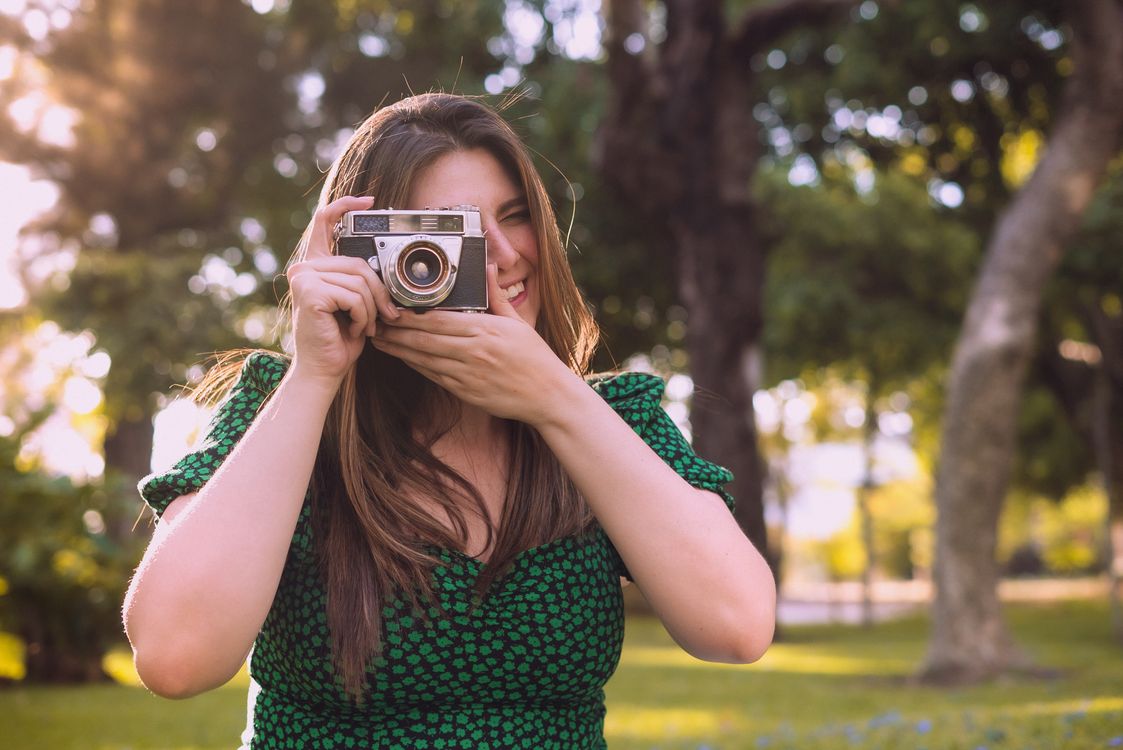 A Smiling Woman in Green Dress Holding a Camera · Free Stock Photo
