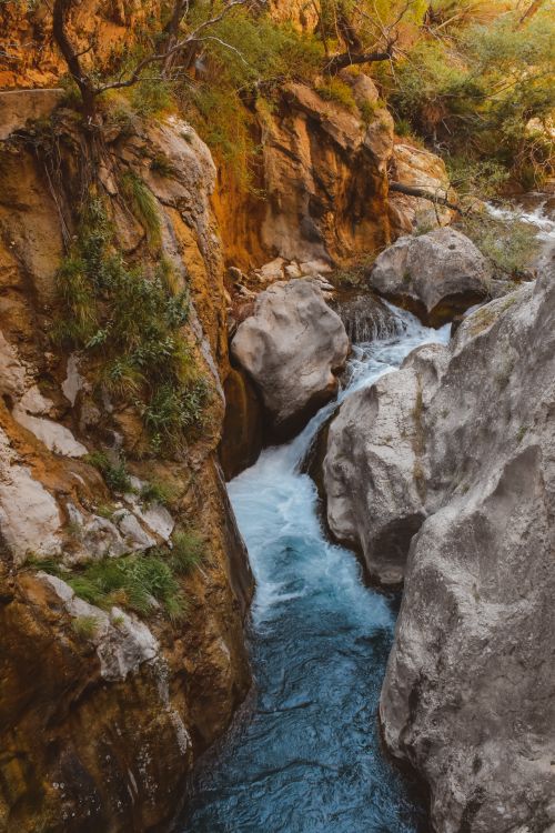 Free A picturesque canyon featuring a serene stream flowing between rocky formations, perfect for nature enthusiasts. Stock Photo
