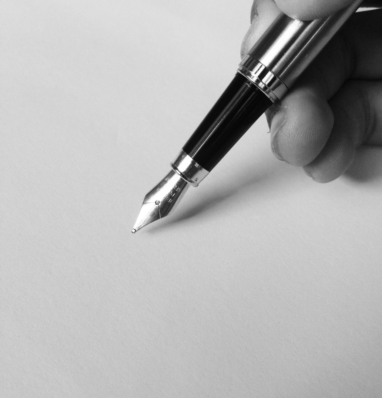 A person holding a fountain pen and writing on blank paper — fountain pen daily writing feel