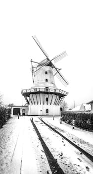 这张黑白照片中，丹麦科灵的风车被冬雪覆盖，显得标志性而宁静