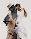 Happy couple in elegant clothes kissing under gray sky