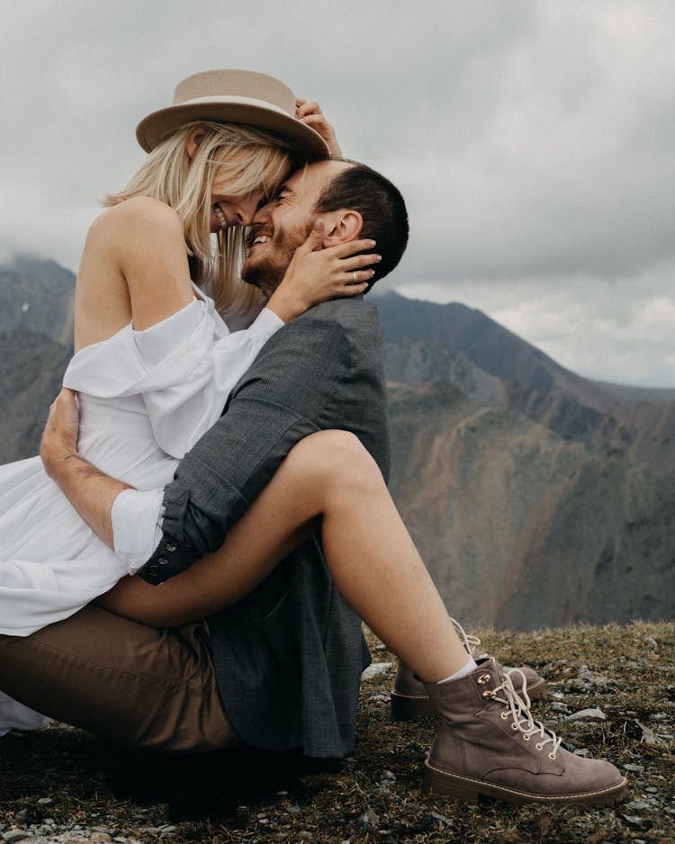 Romantic Couple Sitting In Nature Against Mountains In Daylight