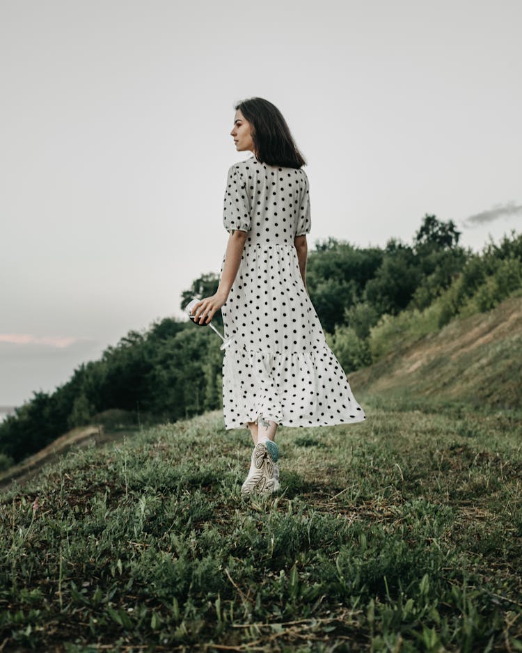 Woman In Polka Dot White Dress Walking In Countryside