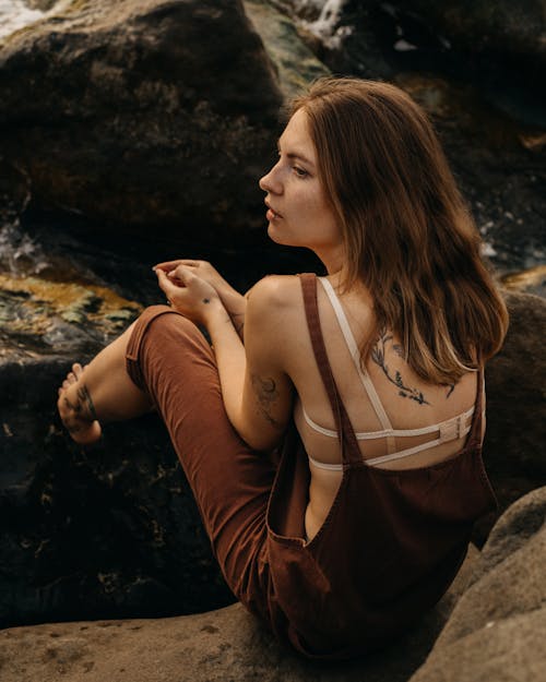 Female with bare shoulders sitting on rocks