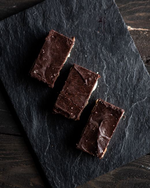 Top view of square cut chocolate pastries served on slate board in row