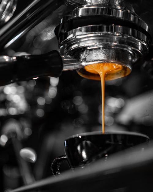 Free Rich espresso flowing from a machine into a cup, highlighting the art of coffee brewing. Stock Photo
