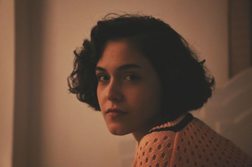 Free A moody indoor portrait of a woman with curly short hair in warm lighting. Stock Photo
